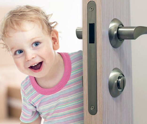 A child trying to open a door equipped with a childproof lock.