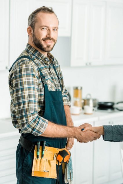 smiling-handsome-plumber-and-customer-shaking-hands-in-kitchen.jpg